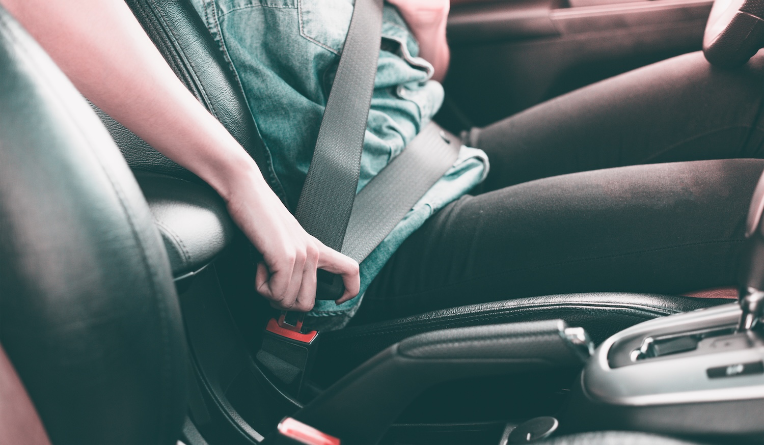 A woman in a car plugging in her used car seat belt to start driving
